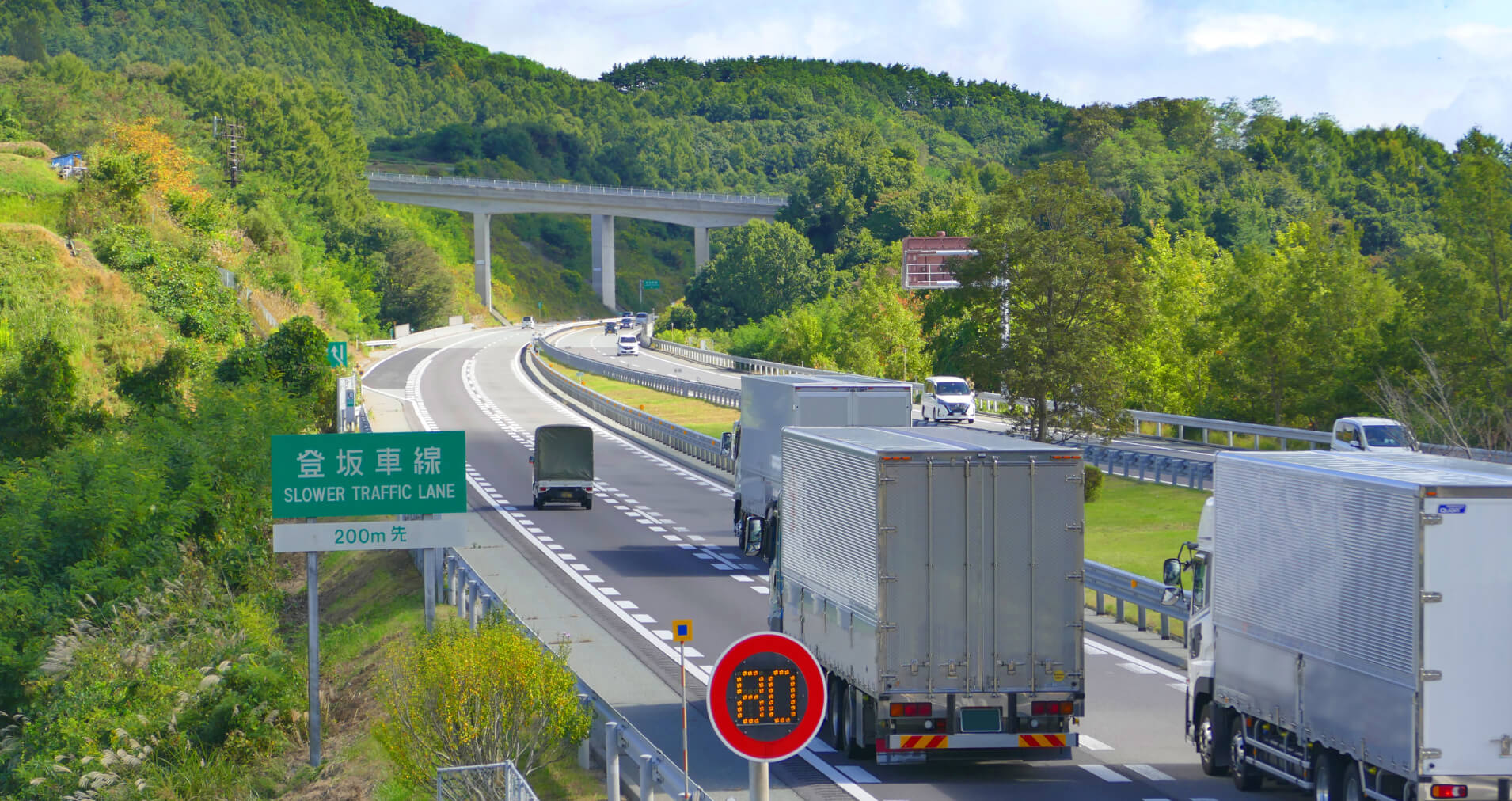 柳井海運株式会社の大型トラックが高速道路を走行している写真。安定輸送をアピールする画像。